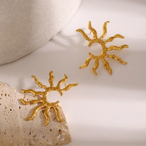 Close-up of golden sunflower stud earrings with fluid lava texture on a stone surface