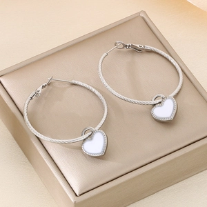 Silver twisted rope hoop earrings with white heart pendants on luxury display