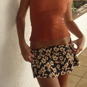 Detailed close-up of a floral print mini skirt paired with a brown pleated crop top sleeveless vest