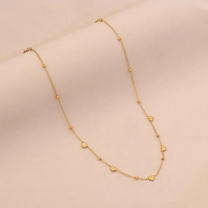 Detailed view of a gold heart necklace with small diamonds on a soft fabric background