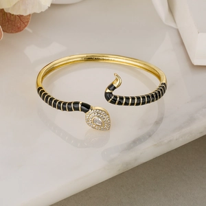Macro shot of gold snake bracelet with black enamel, pave zircon and water-drop main stone