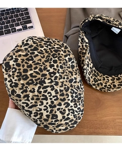 Detail view of leopard print beret hat showing texture and black inner lining on wood