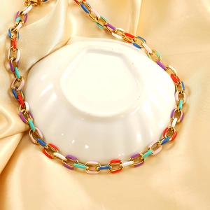 Collier à maillons dorés avec émail multicolore sur fond de satin champagne brillant