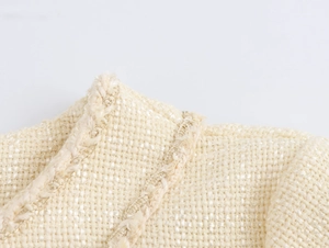 Detailed macro shot of cream tweed fabric texture and woven pattern on the dress collar