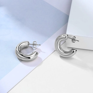 Macro view of polished silver thick C-shape hoop earrings with smooth metallic finish