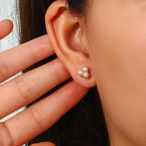 Macro detail of triple white pearls arranged in a triangle on a gold stud earring
