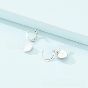 Detail view of silver heart-shaped drop earrings with textured finish and hoop closure