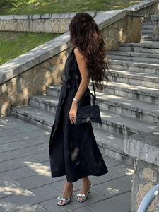 Detail showing a black sleeveless shirt dress with a waist tie and stylish accessories