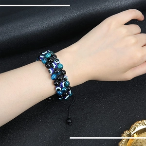 Detailed view of triple-layered braided evil eye bracelet worn on a male wrist