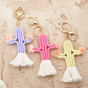 Detail of woven cactus keychains in purple, pink, and yellow with white cotton tassels
