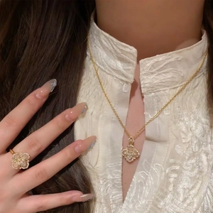 Detail showing the polished golden clover necklace and ring set with sparkling zircons