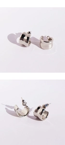 Macro shot of silver mirrored irregular thick C-shaped hoop earrings with metal texture