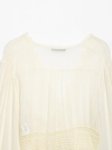 Detailed macro view of pleated ivory chiffon texture and lace neckline on a women's shirt