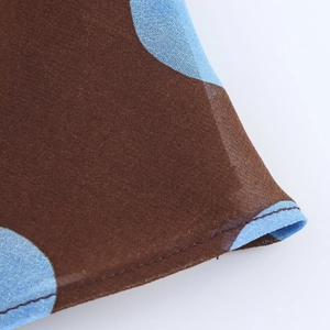 Close-up of brown chiffon fabric with blue polka dots and premium stitching details