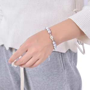 Detailed view of white howlite beaded bracelet with a silver compass charm on wrist