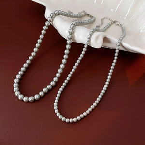 Detail view of large and small grey pearl necklaces on a decorative white shell tray