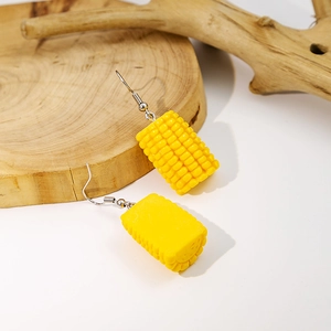 Macro detail of creative resin corn drop earring with silver hook on a wood slice