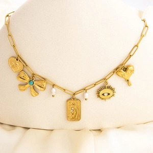 Detail of 18k gold paperclip necklace featuring sun shell and winged heart charms on a model
