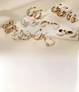 Détail des boucles d'oreilles cœur et forme C en acier titane doré et émail blanc