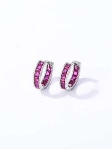Vista macro de pendientes de aro plateados con circonitas rojas talla princesa
