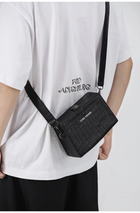 Detail showing the black crocodile embossed box bag worn with a long shoulder strap