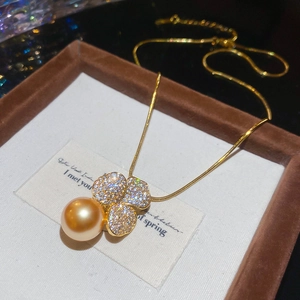 Detailed close-up of a gold-plated flower and pearl pendant resting in a jewelry box