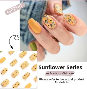 Detail of short sunflower nail tips showing yellow floral patterns and green finish