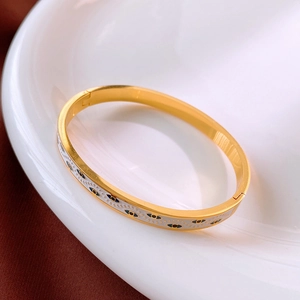 Vue détaillée d'un bracelet œil porte-bonheur doré posé sur une assiette en céramique