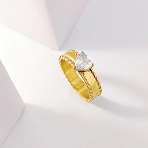 Macro detail of gold ring with heart-shaped crystal and braided texture band