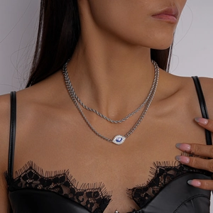 Detail of double-layer silver necklace with evil eye pendant and blue enamel inlay