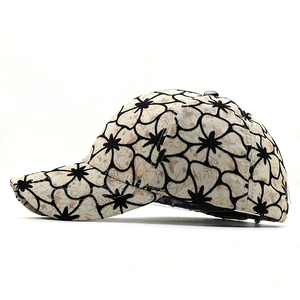 Detailed side view of a beige floral baseball cap with black line flower patterns