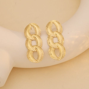 Golden long drop earrings with three brushed metal chain links on a jewelry display