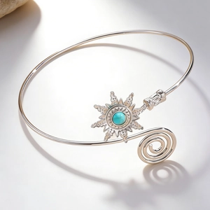 Detail of silver arm cuff featuring a sunburst motif with turquoise stone inlay