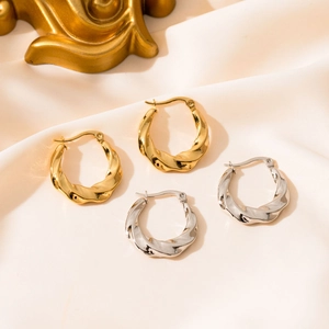 Modern twisted hoop earrings in gold and silver finish on elegant silk background