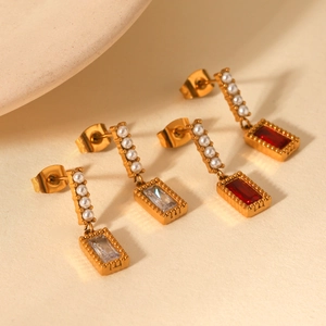 Detailed macro view of gold-plated earrings with pearls and rectangular gemstones