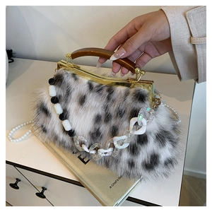 Détail de la pochette peluche à imprimé vache avec poignée en bois et chaîne perle