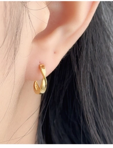 Close-up of a twisted gold ear cuff on a female model's ear showing elegant details