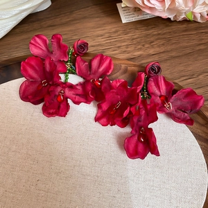 Detail of fabric flower earrings with dark red petals, green beads and teardrop pendant