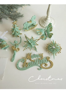 Detail of mint green Christmas ornaments with gold glitter on white tabletop with pine