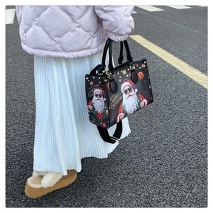 Detail of Christmas tote bag with Santa print and gold hardware shown in street style