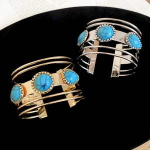 Detail of bohemian open cuff bracelets in gold and silver with turquoise stone inlays