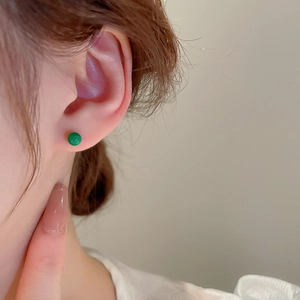Close-up of a glossy green bead stud earring worn on a model ear for minimalist style