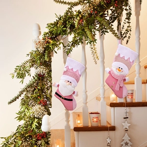 Detail of pink plush Christmas stockings with Santa and Snowman hanging on decor stairs