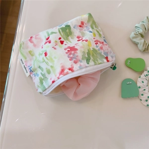 Detail of floral cotton mini pouch with zipper showing textured fabric and simple wish tag