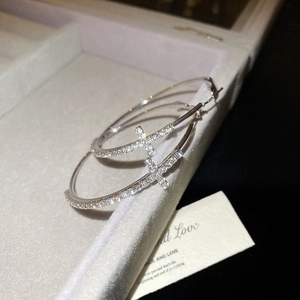 Détail de créoles argentées avec breloques croix étincelantes sur doublure de boîte à bijoux