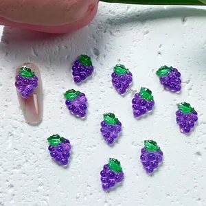 Detailed view of resin purple grape nail art charms on stone background with floral decor