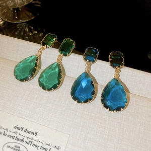 Detailed macro view of vintage gold-plated drop earrings with green and blue crystals