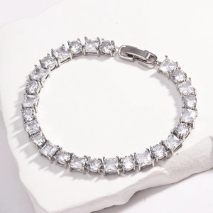 Dettaglio di bracciale tennis argento con zirconi tondi e quadrati su superficie in pietra