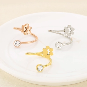 Three minimalist cat paw zircon open rings in rose gold, silver, and gold on a white plate