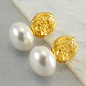 Macro shot of French vintage pearl earrings with textured gold metal and lava finish